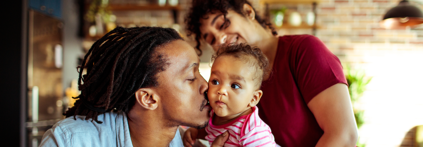 Black father kissing baby girl