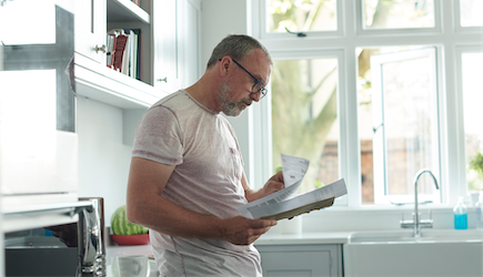 man reading bill with a concerned look on face