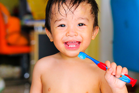 Toddler smiling holding a toothbrush