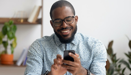 Young Black man looking at his cell phone and smiling