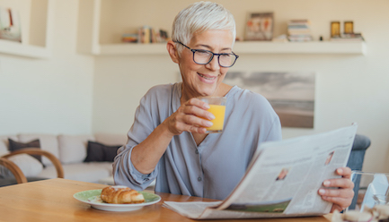 Senior woman reading newspaper at the breakfast table